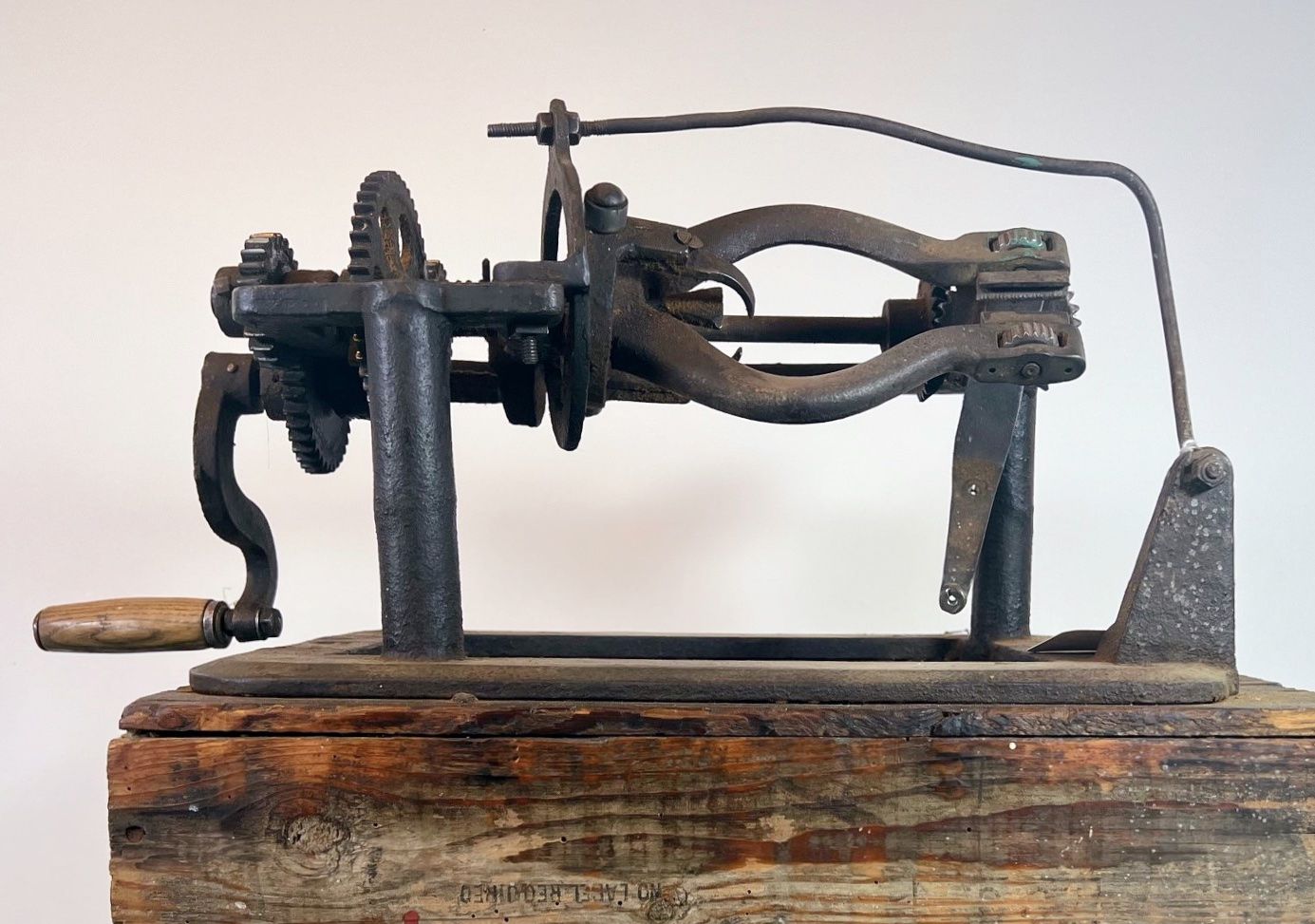 Cast-iron net needle winder with a wooden crank handle, mounted on a weathered wooden block